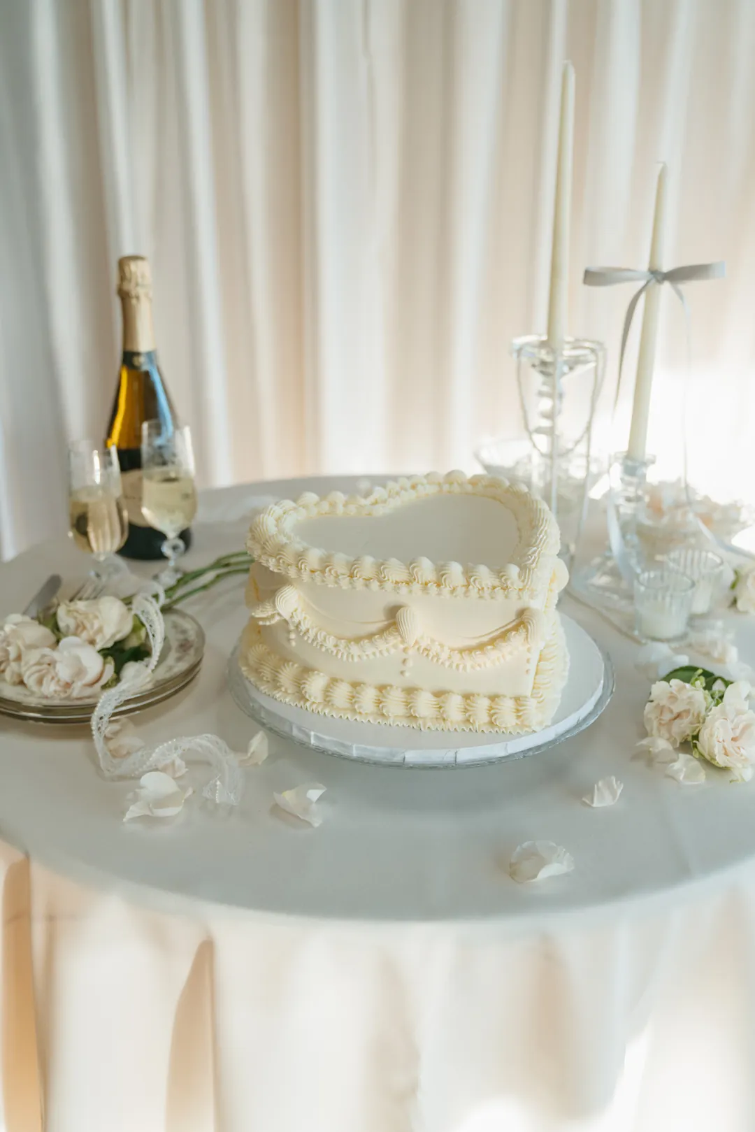 Ivory heart-shaped cake with champagne and white flowers
