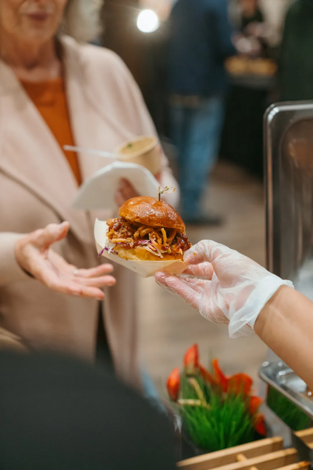 Server handing a Kalua pulled pork slider to a guest