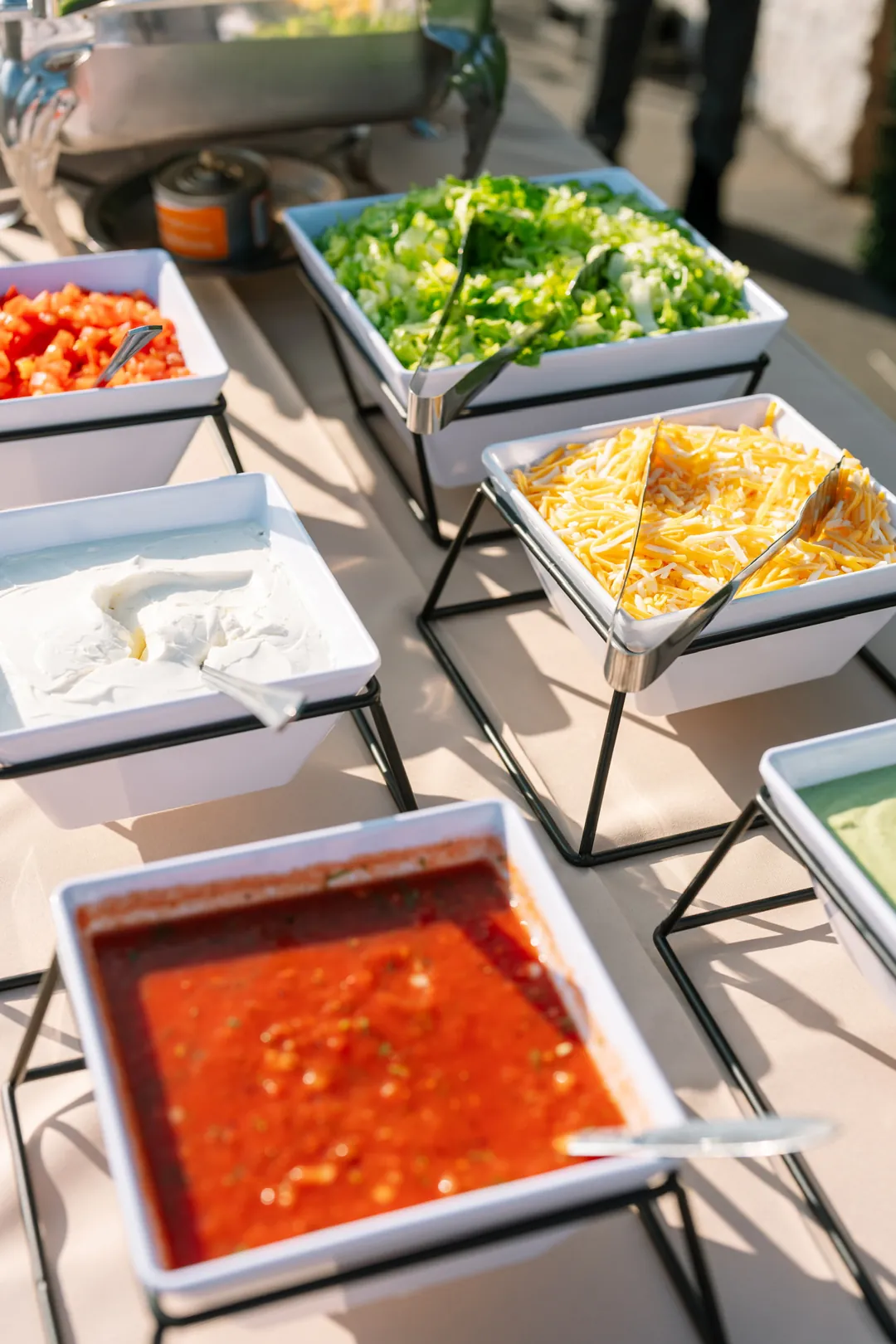 Taco bar toppings including salsa, sour cream, lettuce, tomatoes and shredded cheese