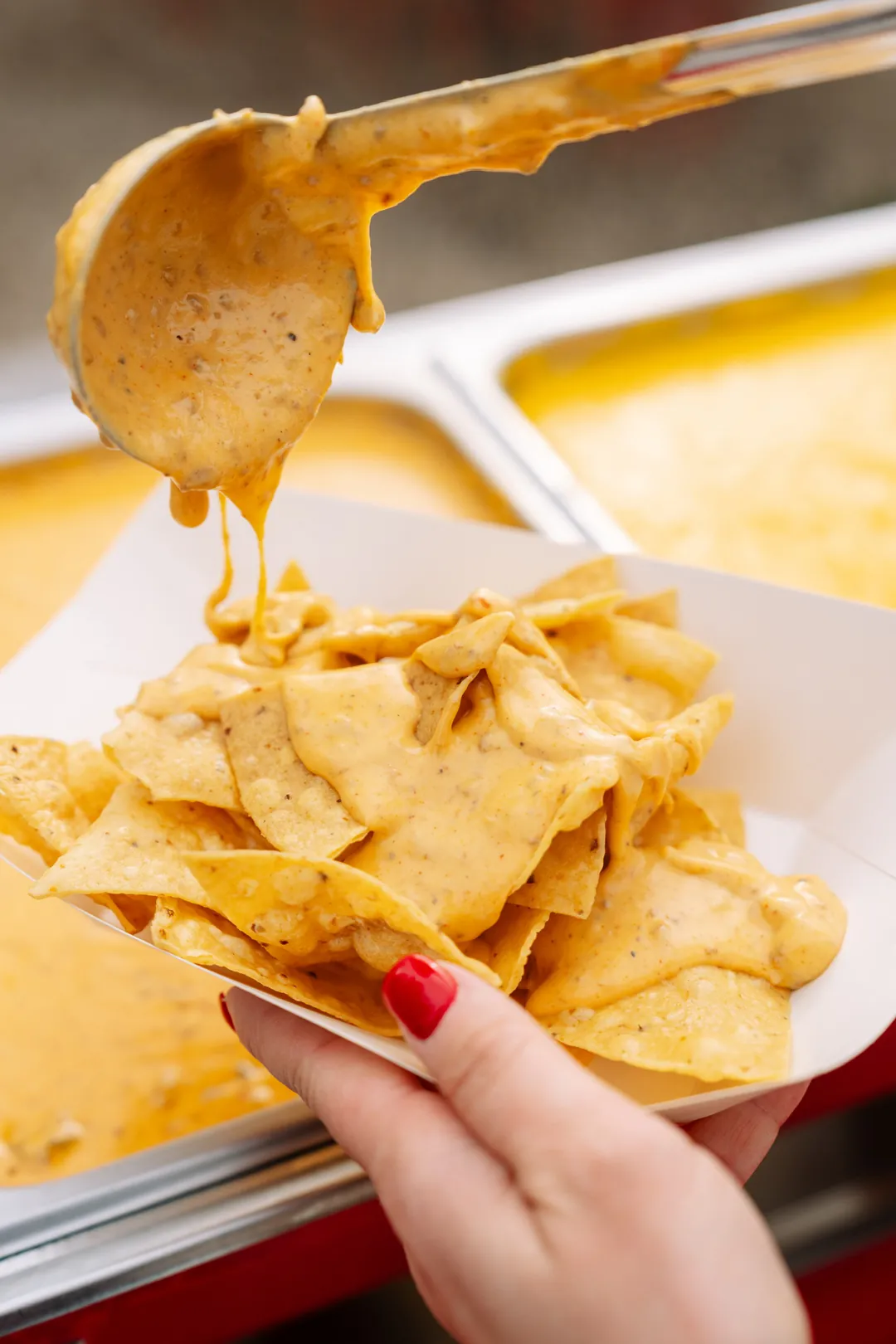 Queso being ladled over tortilla chips