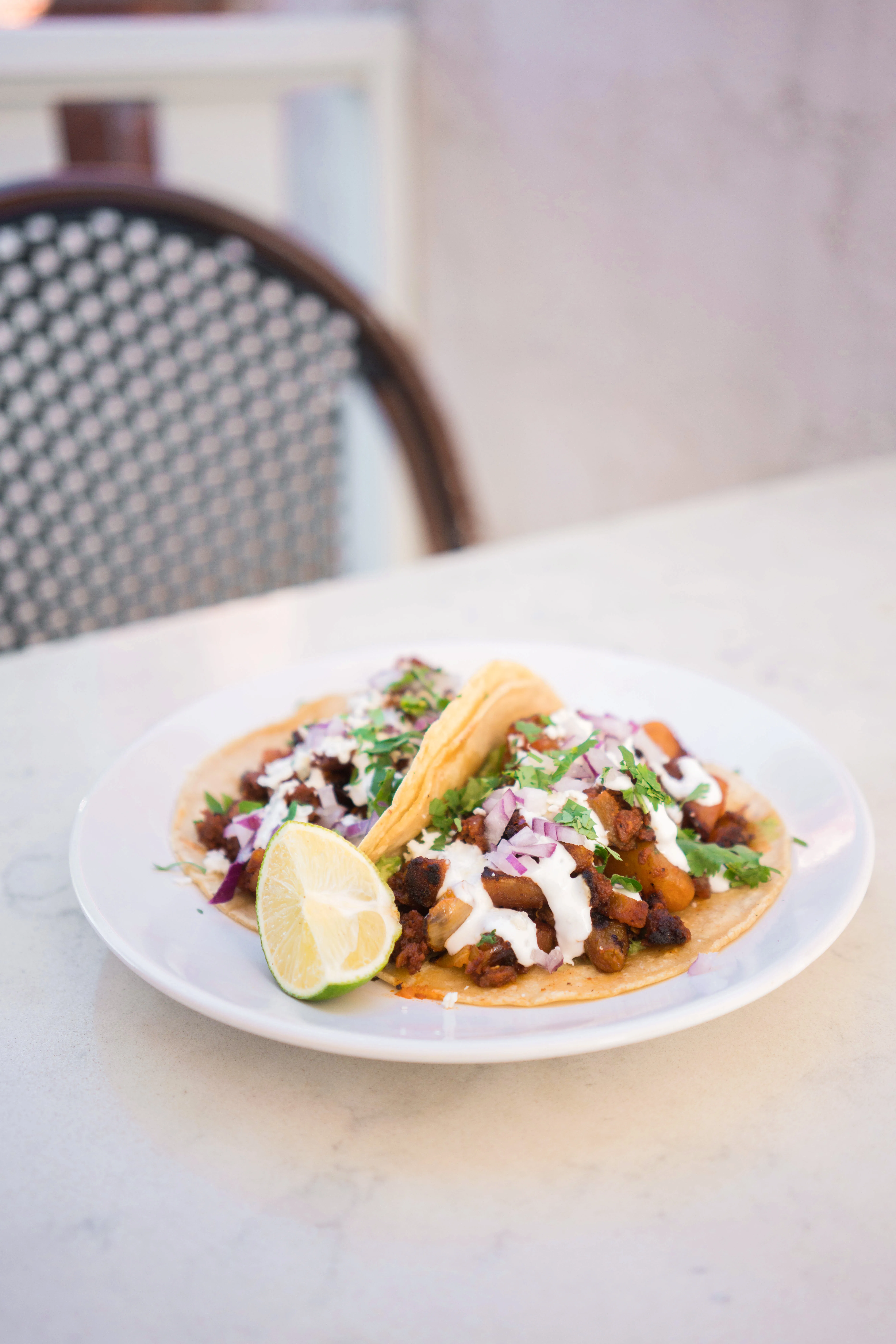 Two chorizo con papas tacos with lime on a white plate