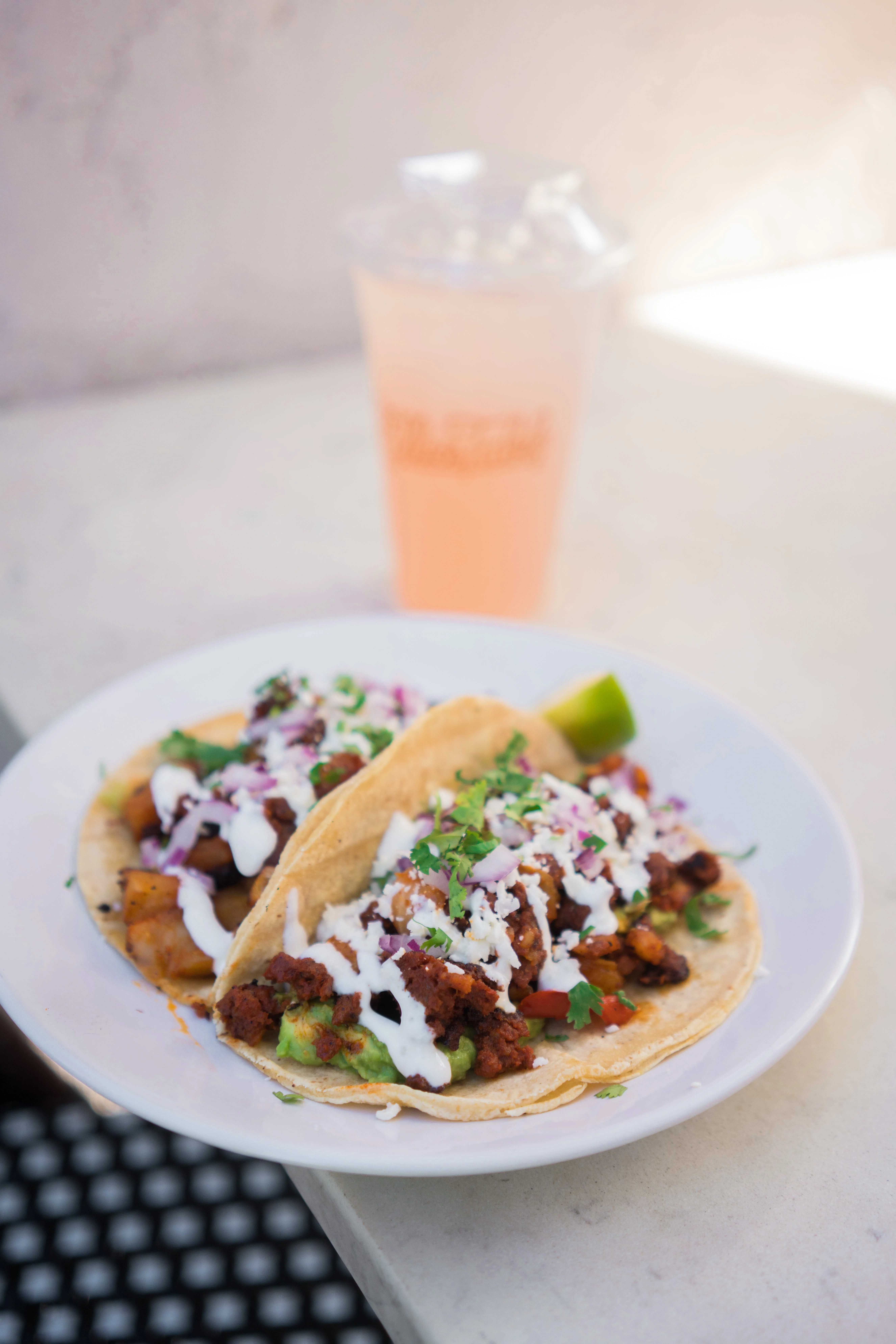 Chorizo con papas tacos beside an iced pink drink