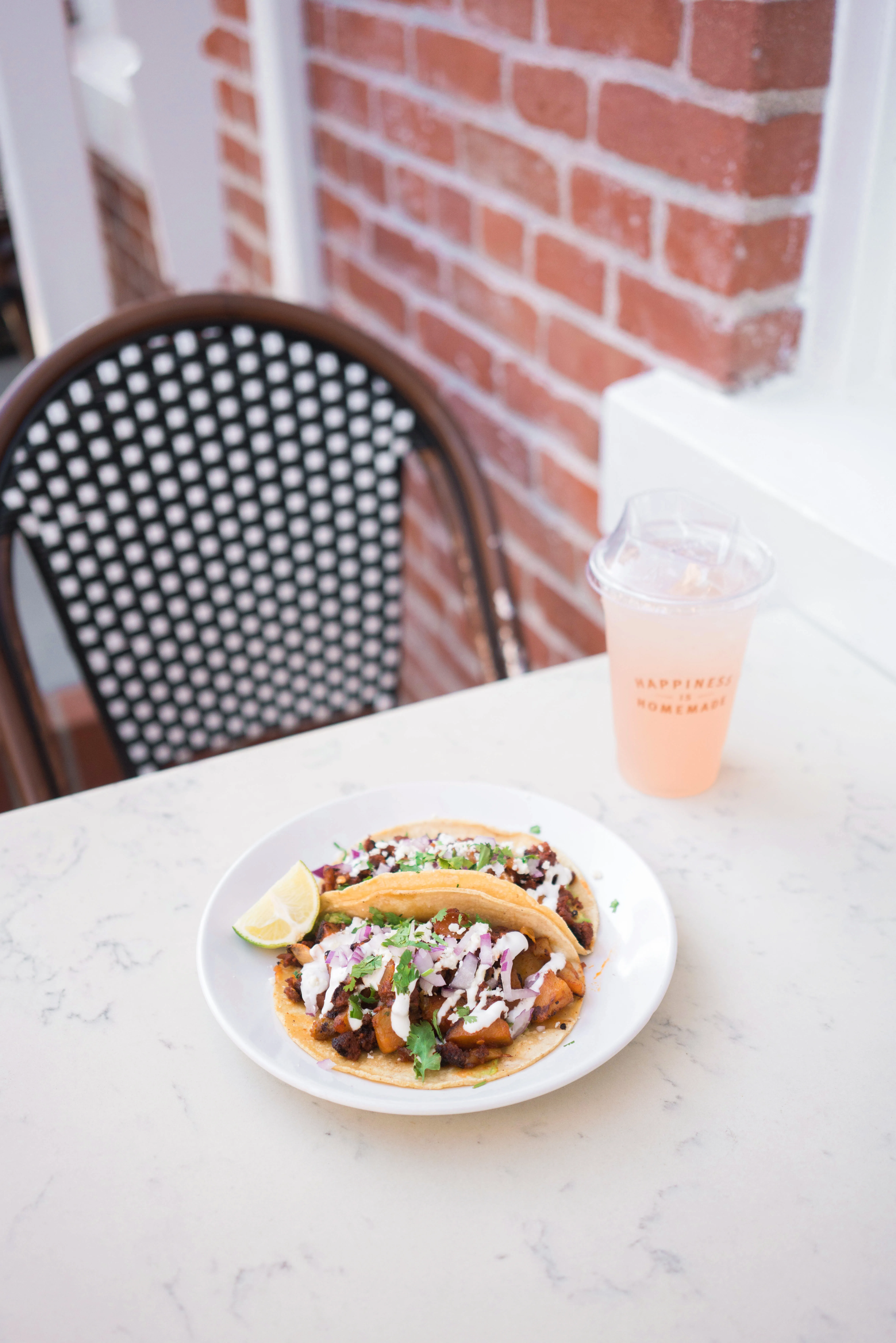 Chorizo con papas tacos and an iced pink drink on the café patio