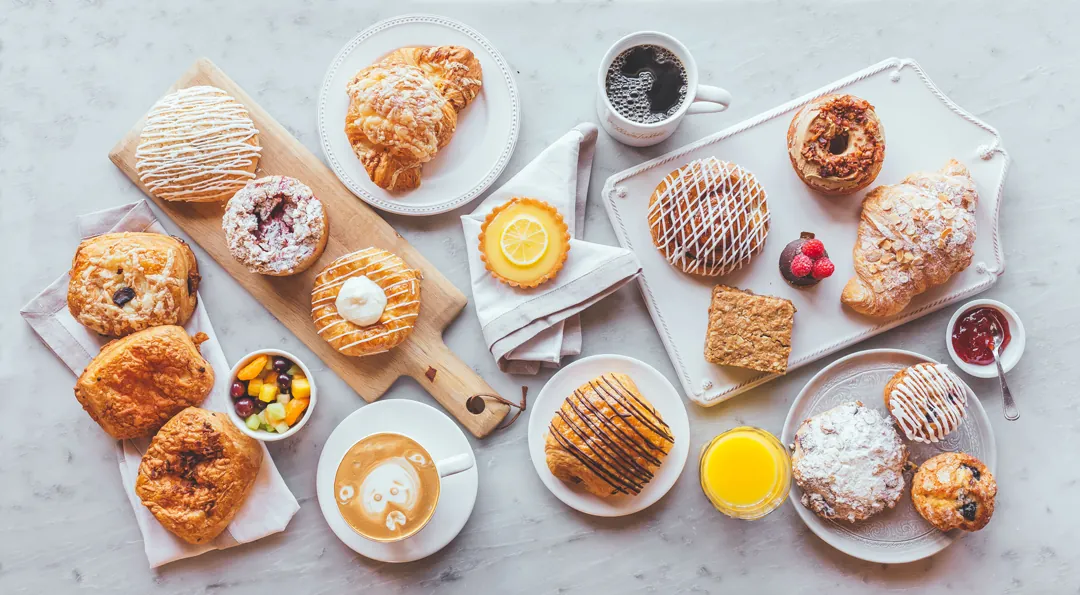 Overhead spread of Ellie’s Table pastries, coffee, juice, jam, and fruit