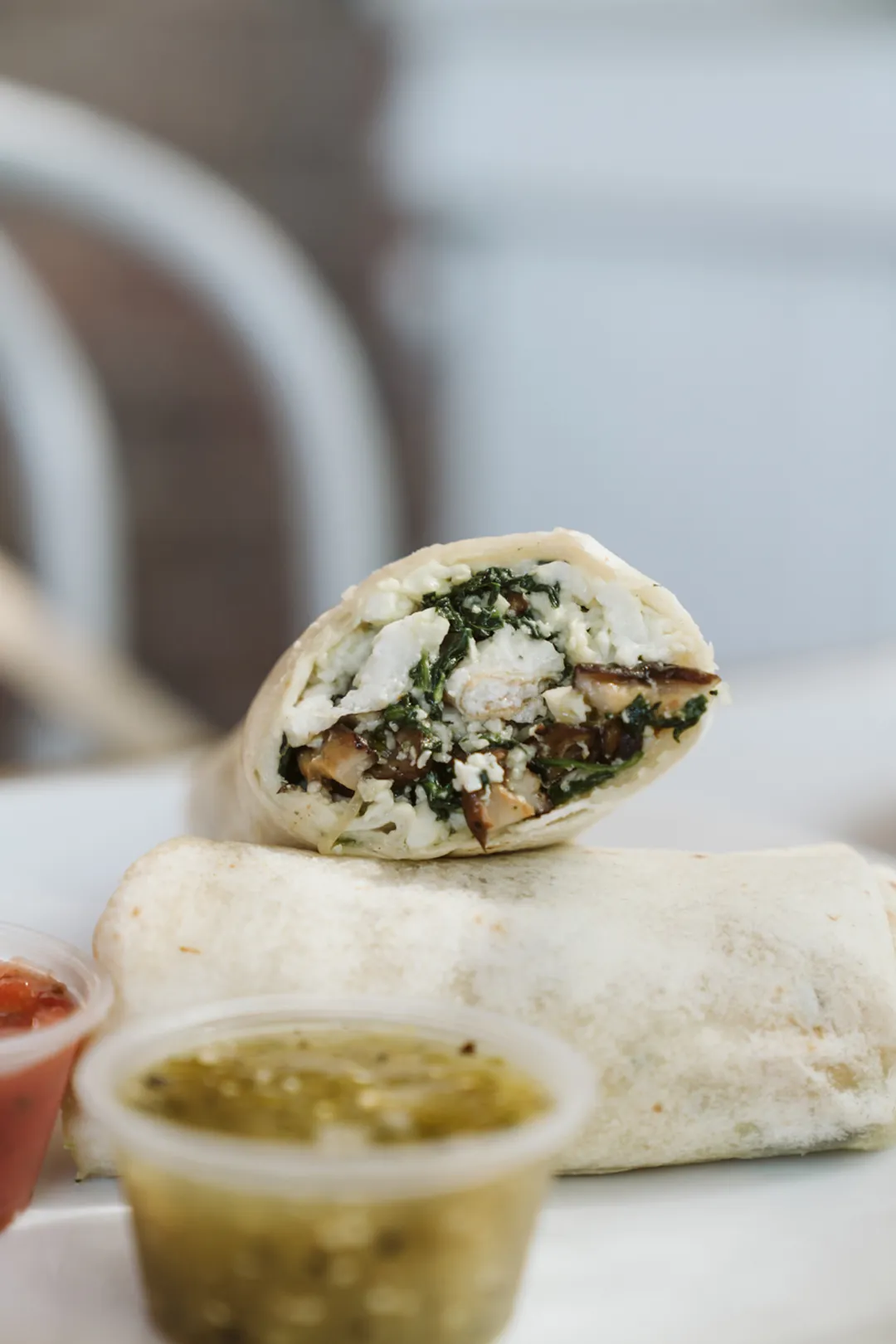 Breakfast burrito with a cup of green salsa