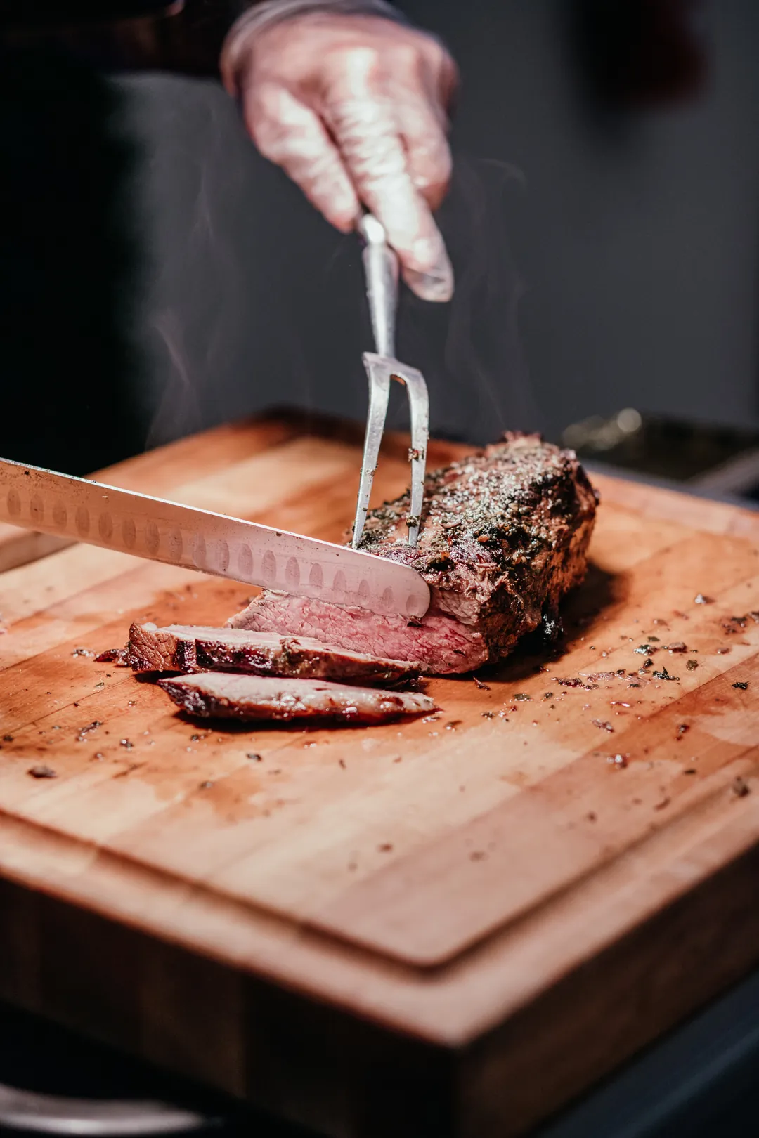 Cook carving a roasted cut of meat on a wooden board