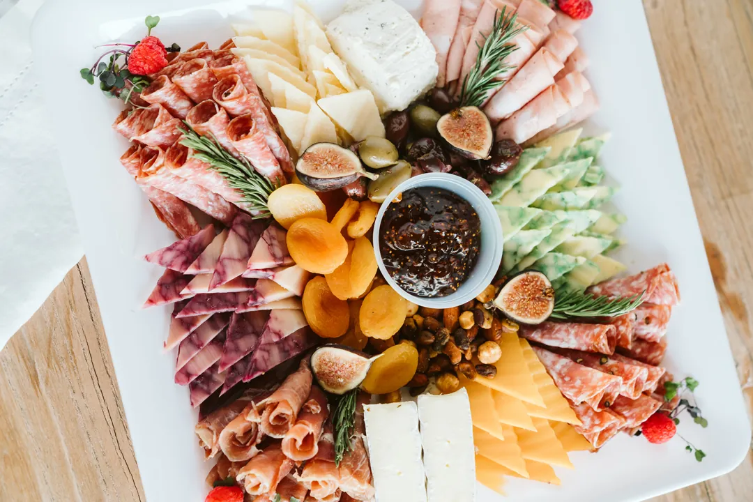 Holiday charcuterie tray with meats, cheeses, fruit, nuts, and preserves