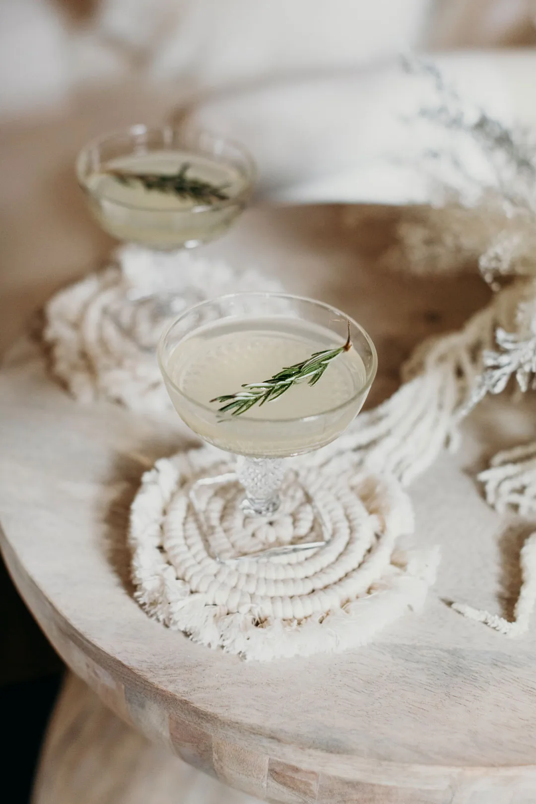 Two pale holiday cocktails garnished with rosemary