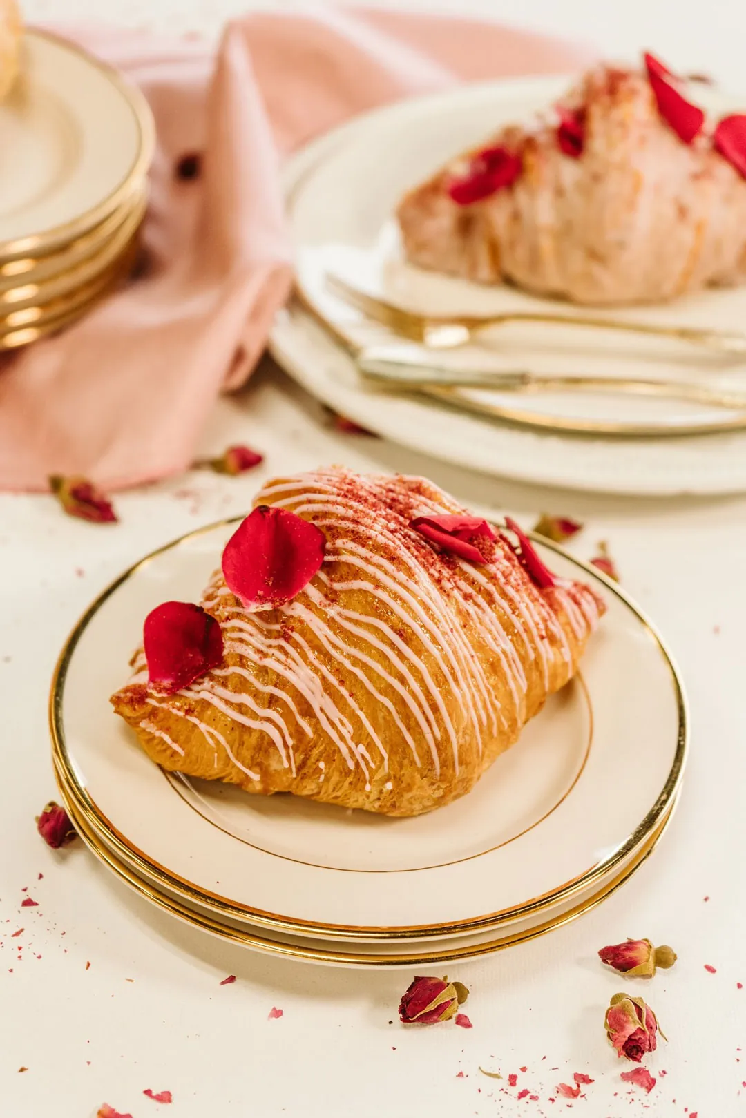 Raspberry rose croissant on a gold-rimmed plate