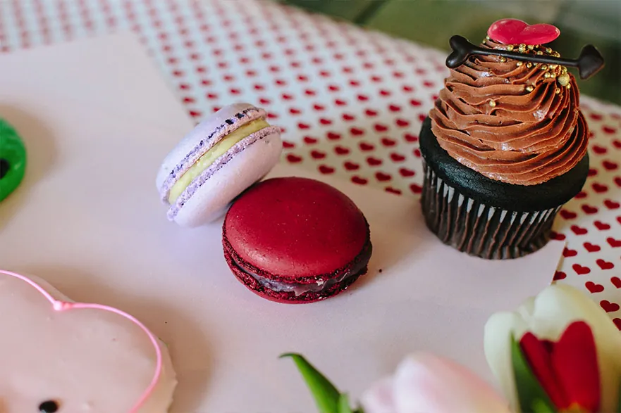 Honey lavender and brandied cherry macarons beside a chocolate cupcake