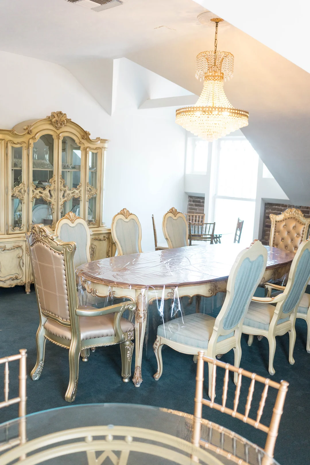 Private dining room with an ornate round table, mixed chairs, and a china cabinet