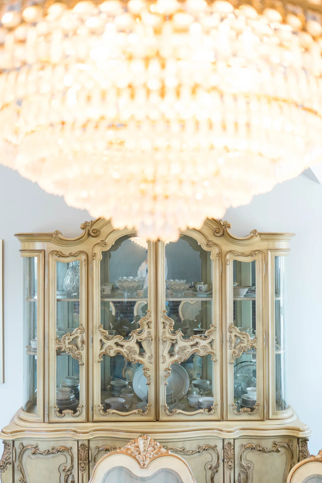 Crystal chandelier hanging above an antique china cabinet