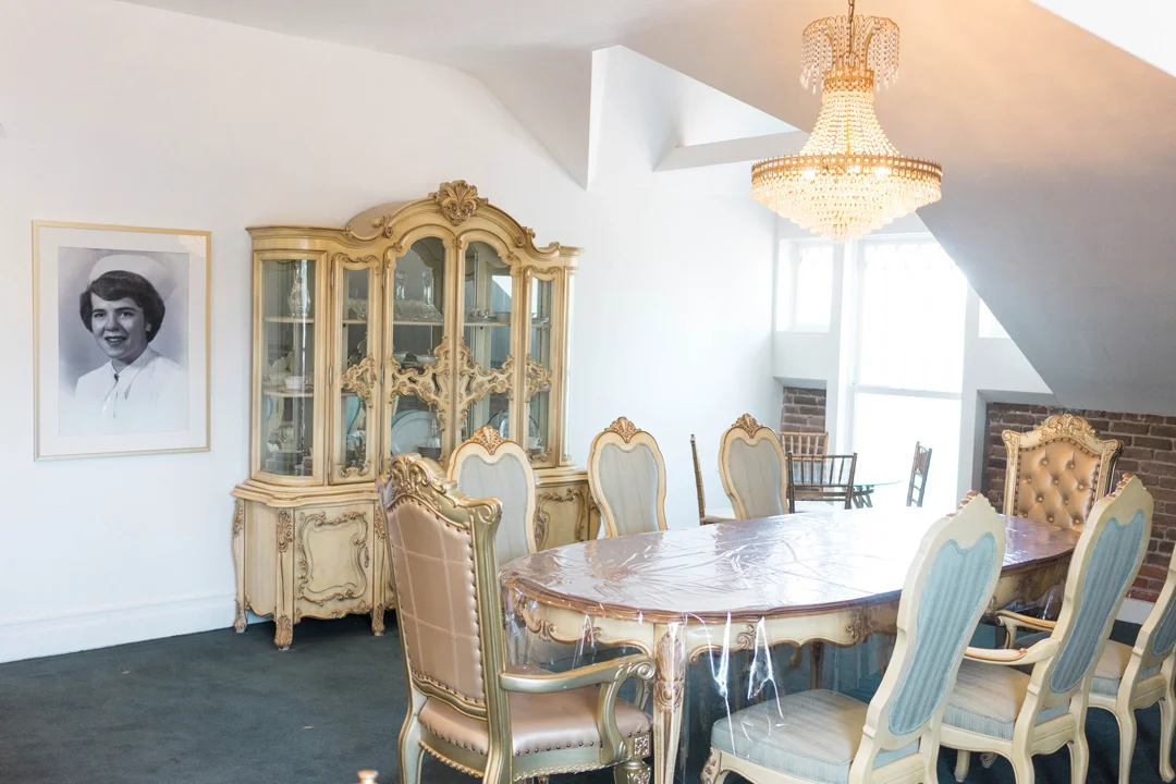 Wide view of the private dining room with antique furniture and chandelier