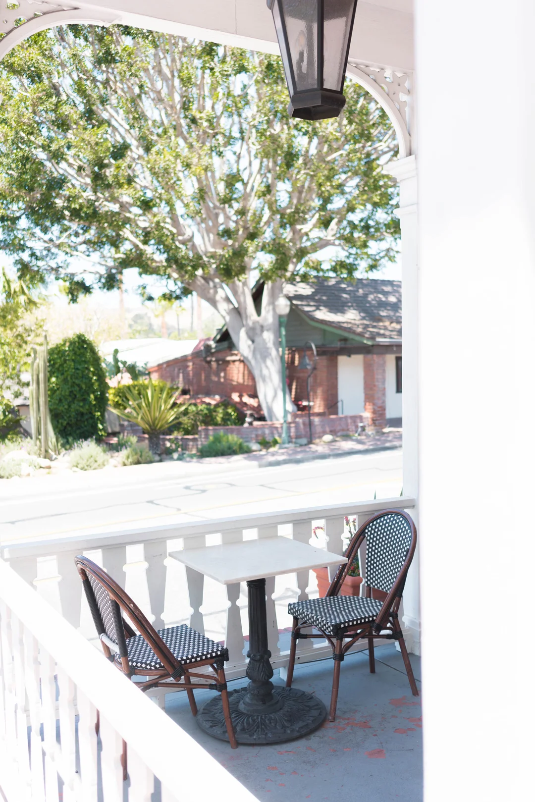 Outdoor café tables overlooking the street from a white porch