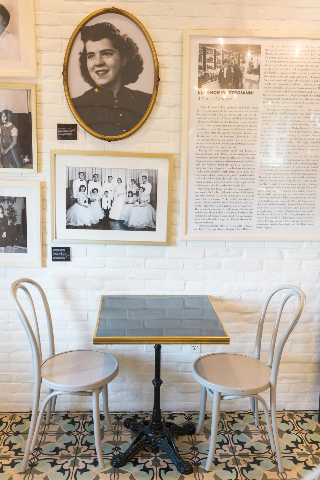 Small café table beneath a wall of framed family photographs