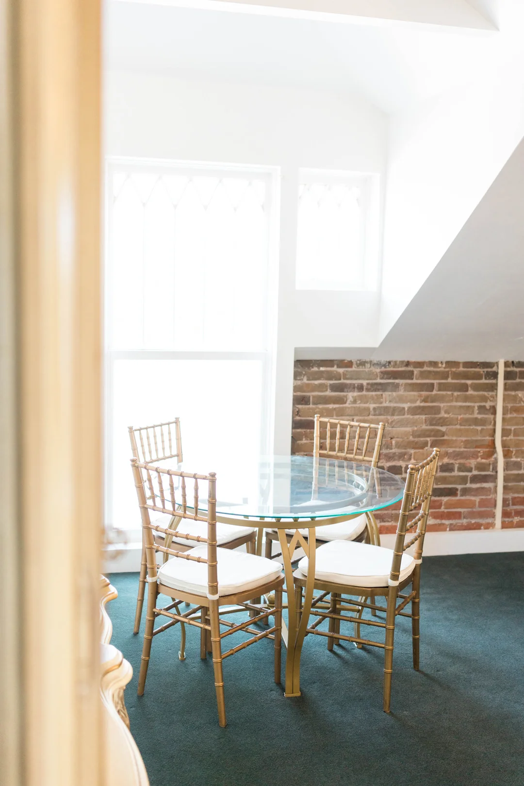 Small round table with gold chairs beside a window