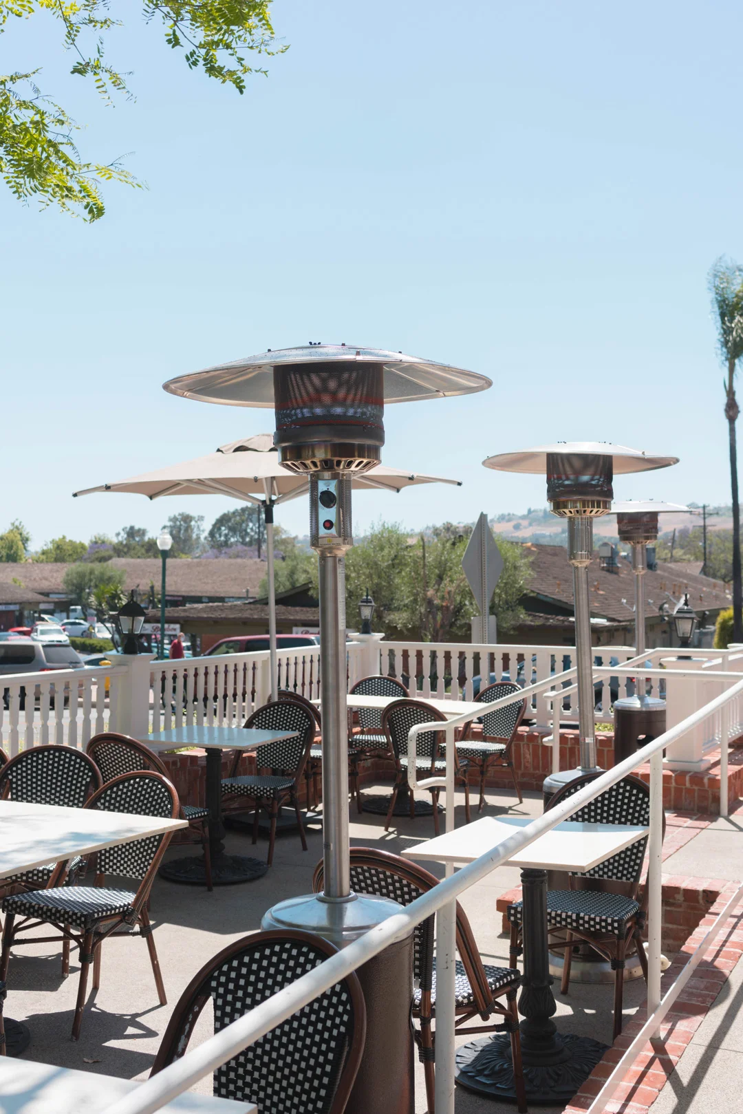 Patio seating with several tall heaters and hillside views