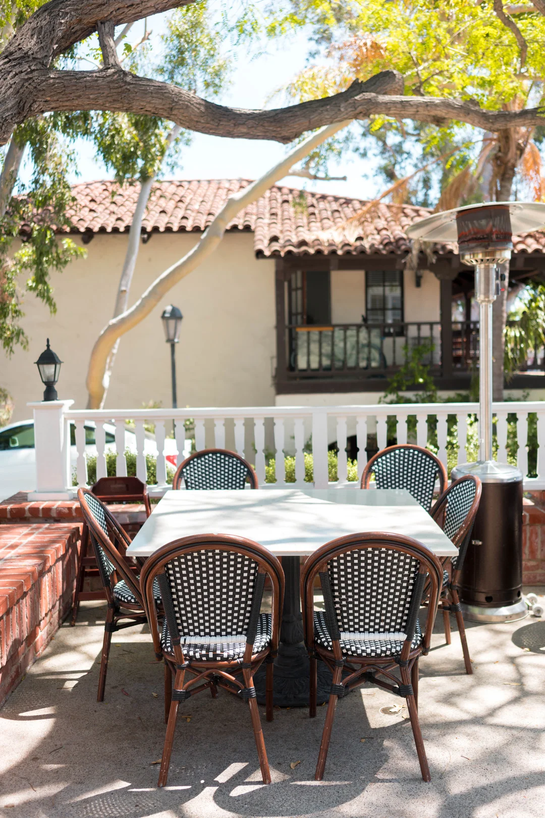 Outdoor table beneath a tree overlooking a neighboring building