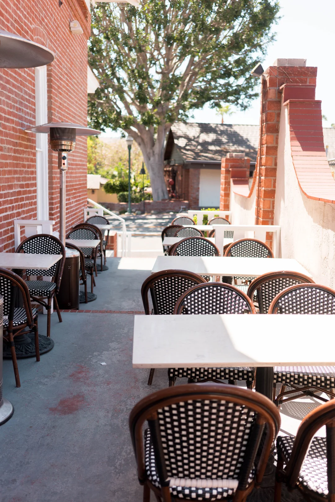 Patio tables between the red brick wall and courtyard