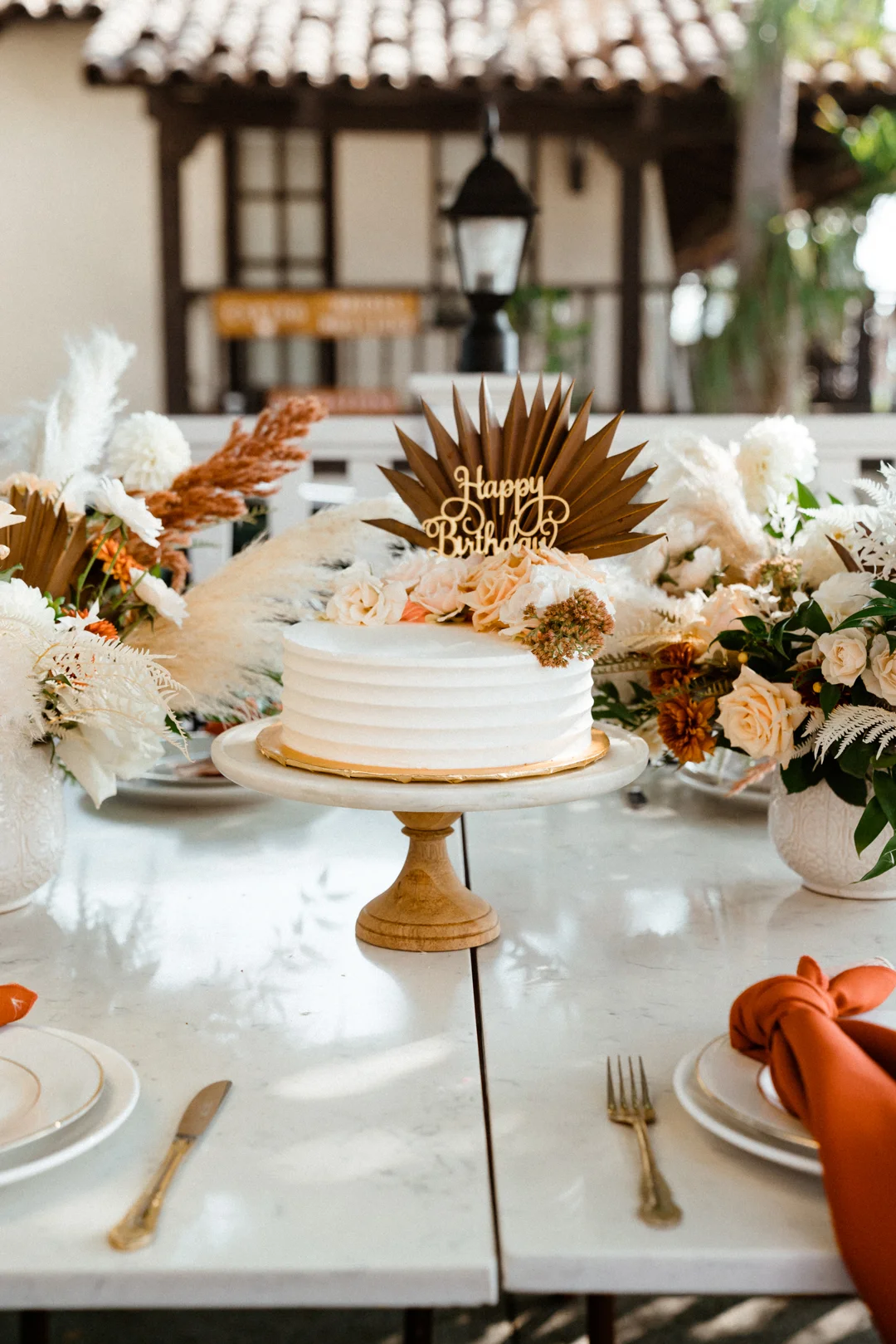 Celebration cake surrounded by white and rust-colored flowers