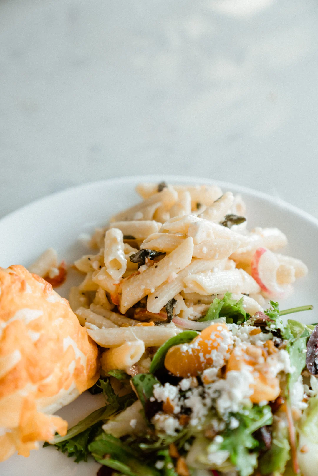 Plate with a sandwich, pasta salad, and greens