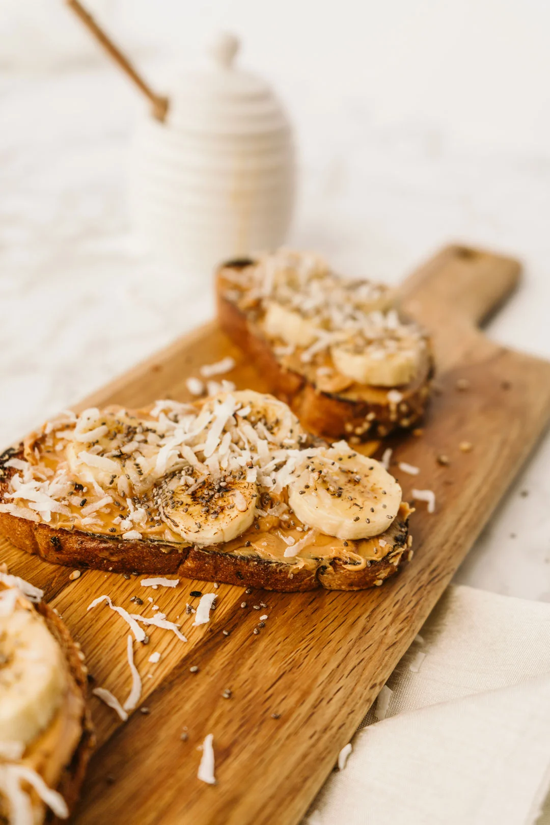Peanut butter toast with caramelized bananas, coconut, and honey on a wooden board