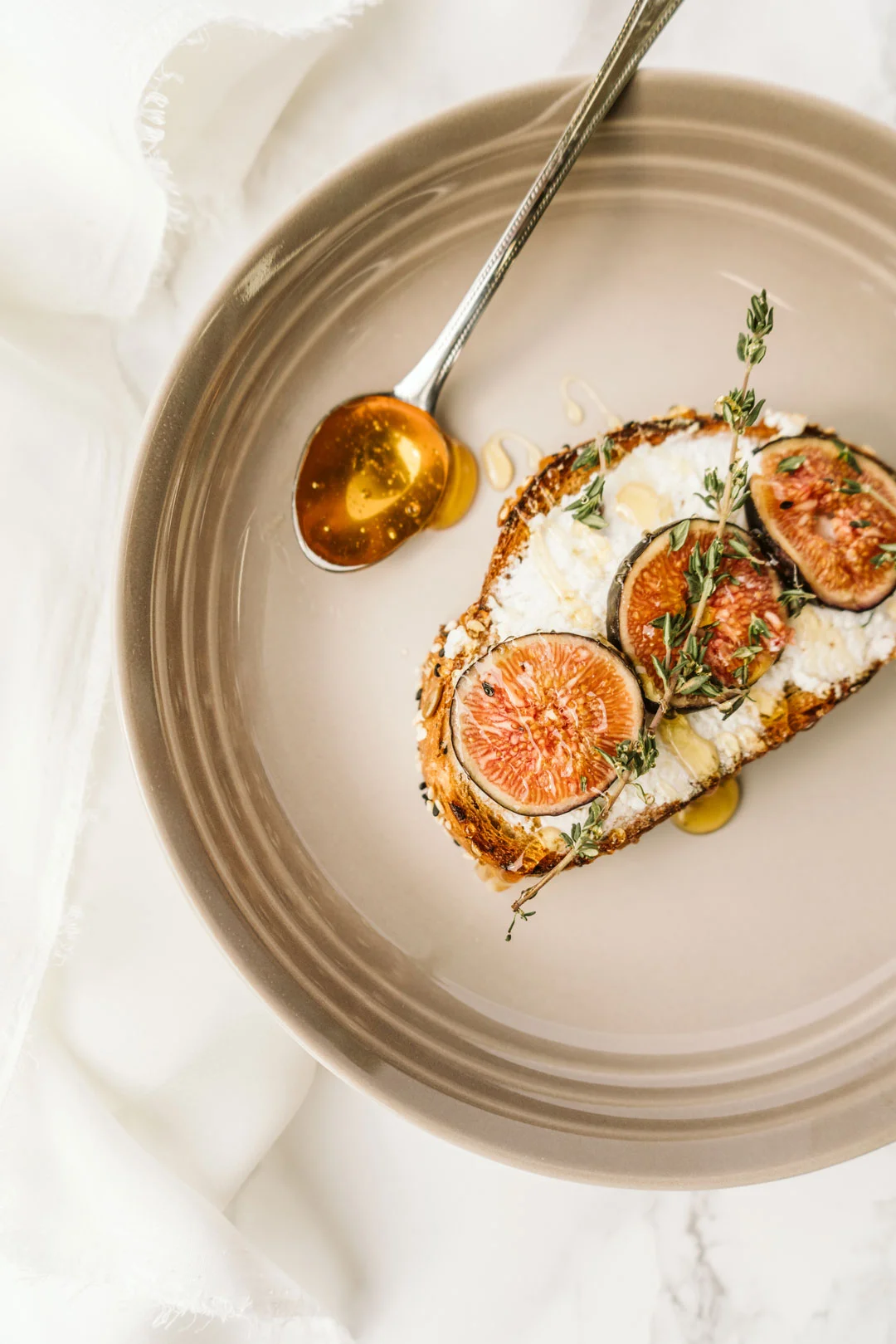 Honey being spooned over ricotta and fig toast