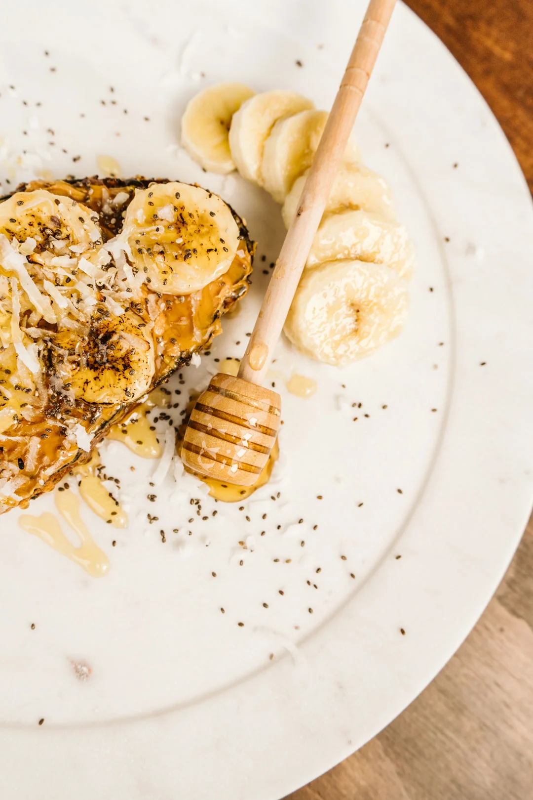 Peanut butter and banana toast beside a honey dipper