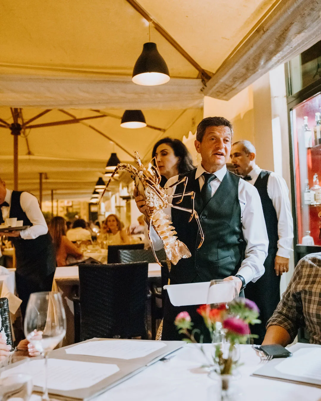 Server presenting a large lobster at Pierluigi restaurant