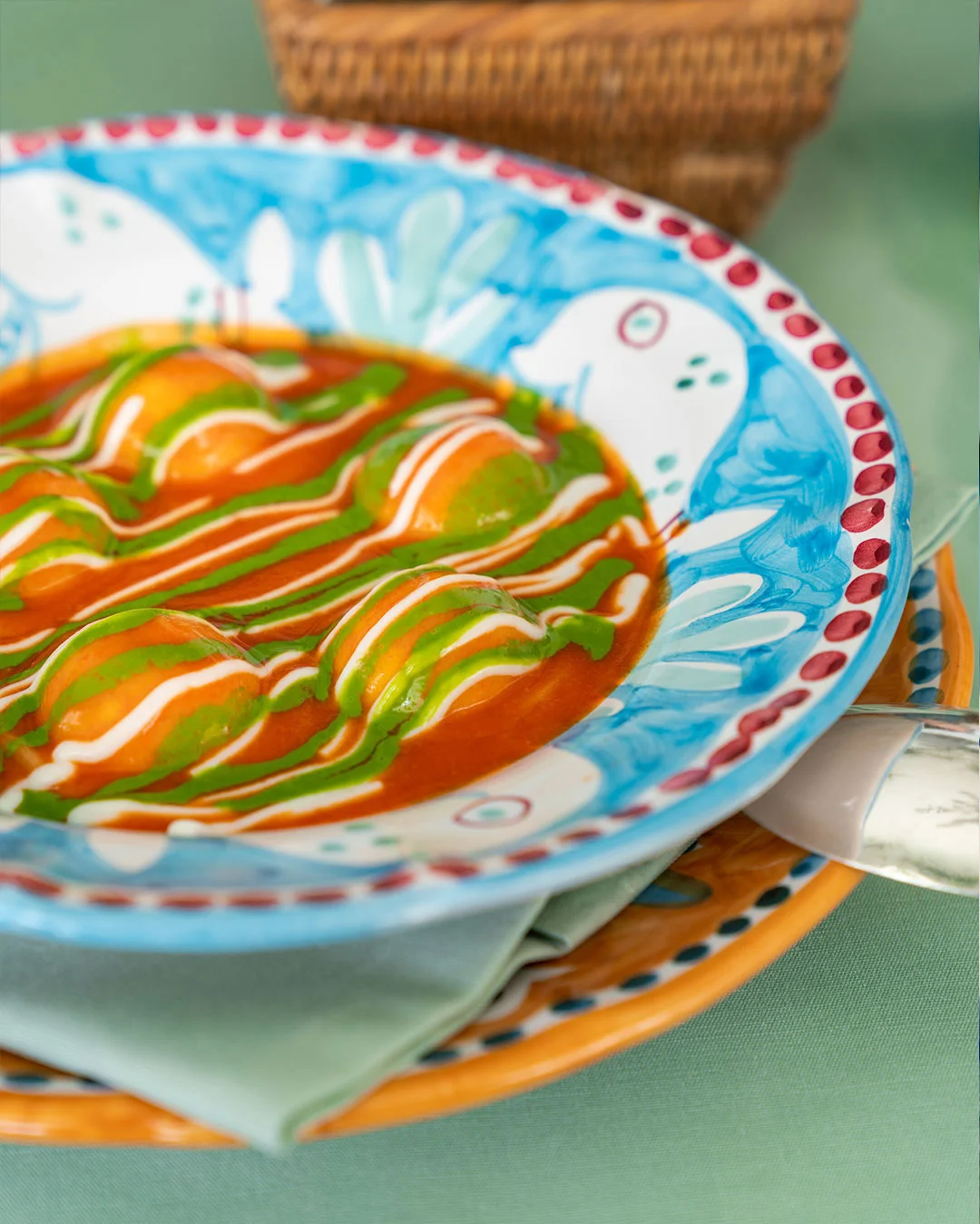 Stuffed pasta arranged in red, green, and white sauces on patterned tableware