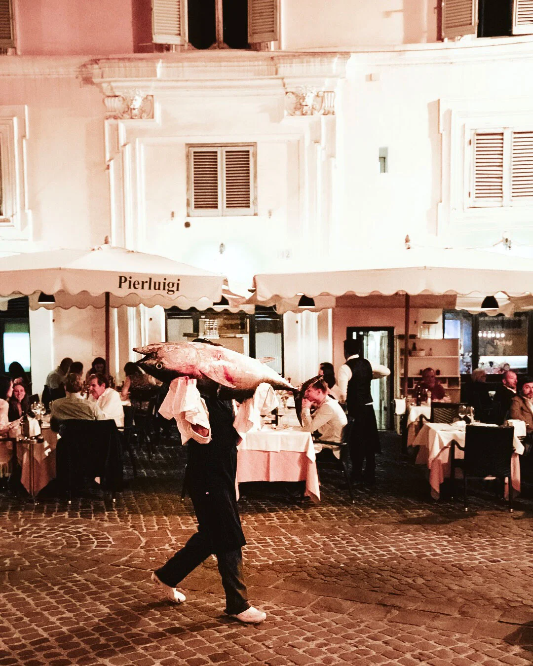 Server carrying a whole fish outside Pierluigi restaurant