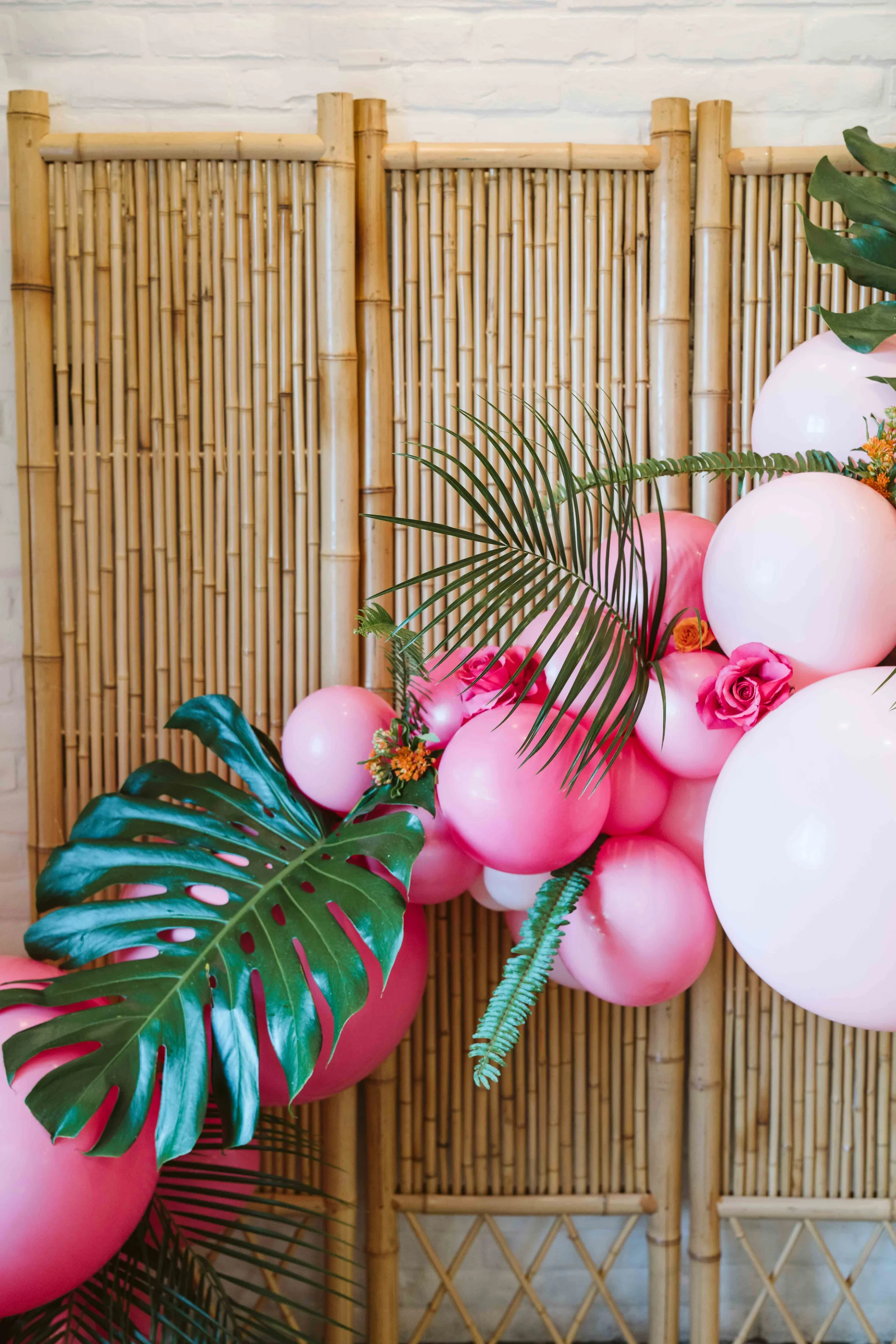 Pink balloon installation beside a tropical photo backdrop
