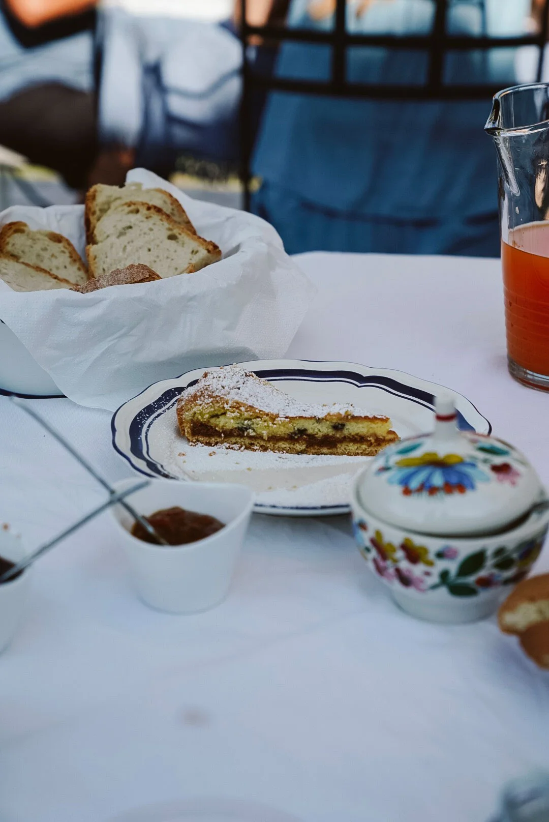 Powdered-sugar tart slice, bread, and juice on a dining table
