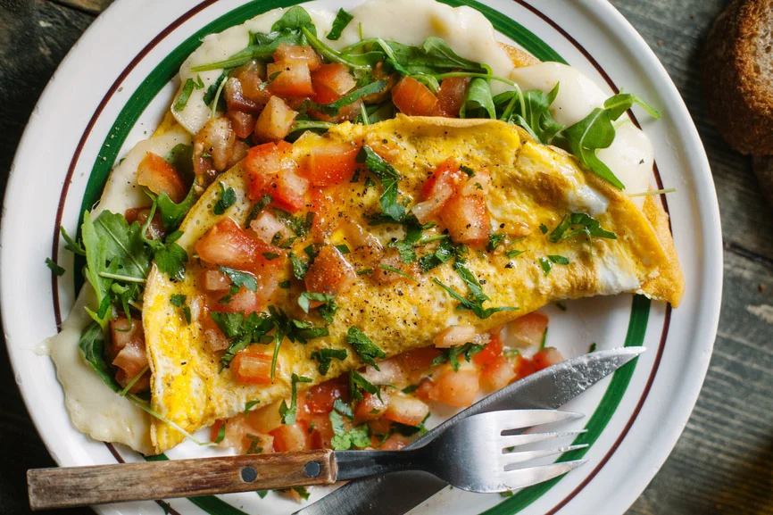 Omelet topped with pico de gallo and greens