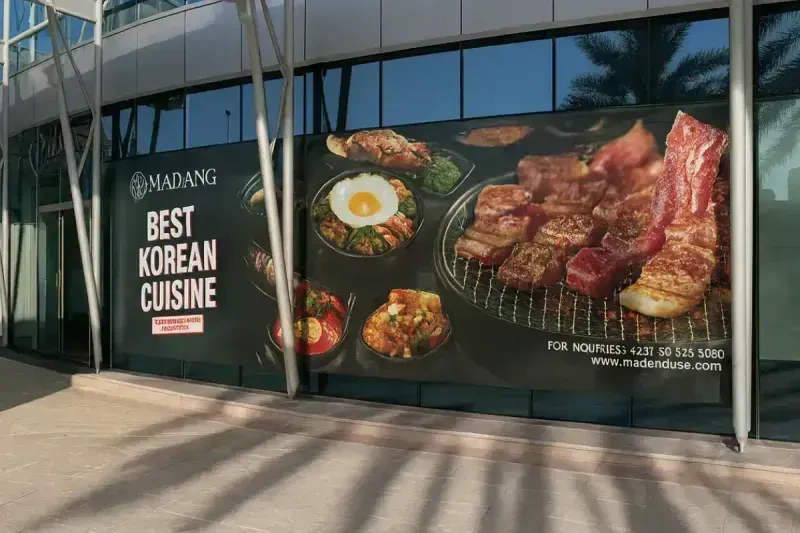 Madang Korean Restaurant promotional window graphics at Holiday Inn Abu Dhabi installed under strict overnight schedule constraints.