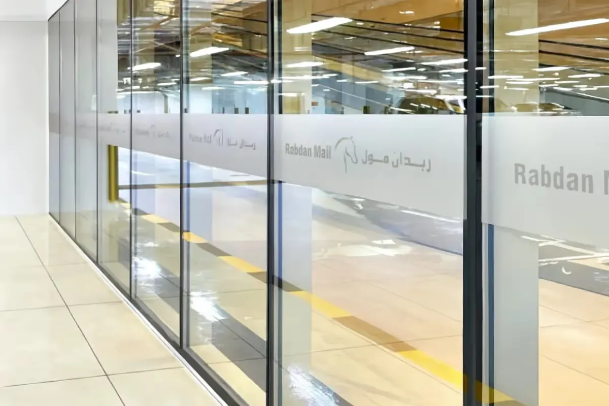 Reverse-cut frosted glass film achieving negative-space logo effect through precision cutting technology for mall common area branding