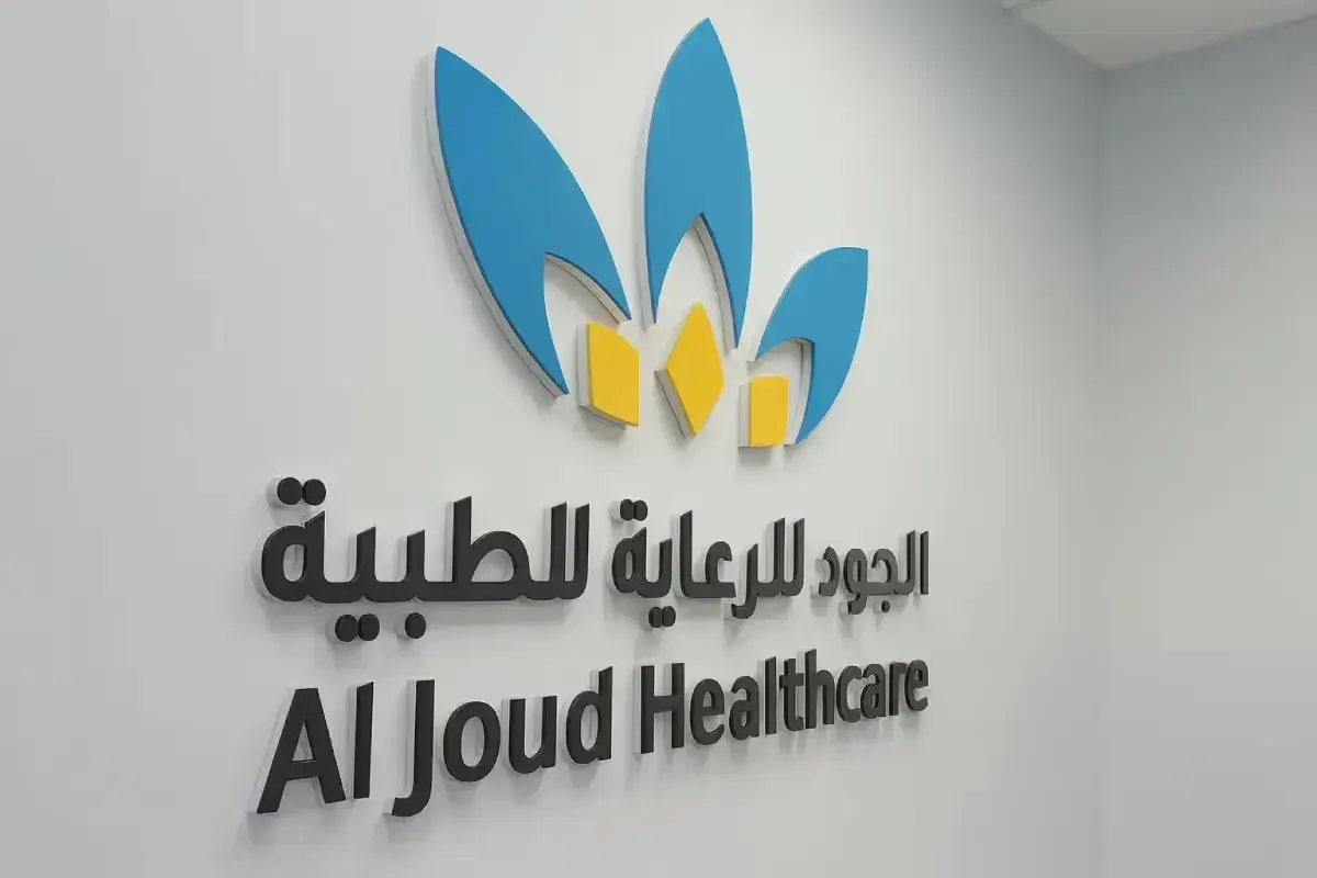 Three-dimensional signage solution for healthcare facility reception area, combining edge-lit logo elements with raised Arabic and English lettering for professional brand presence.