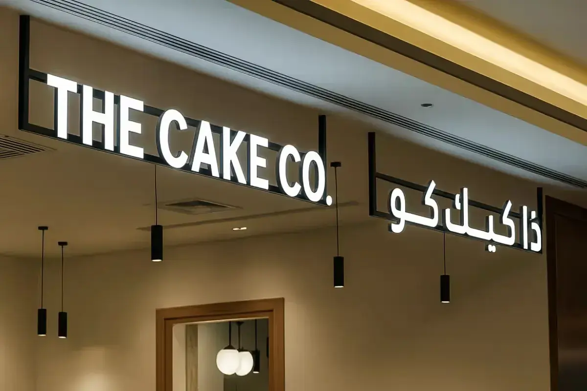Ceiling-suspended dimensional letter installation for bakery storefront, featuring illuminated acrylic faces on metal framework creating elevated floating signage visible throughout mall corridor.