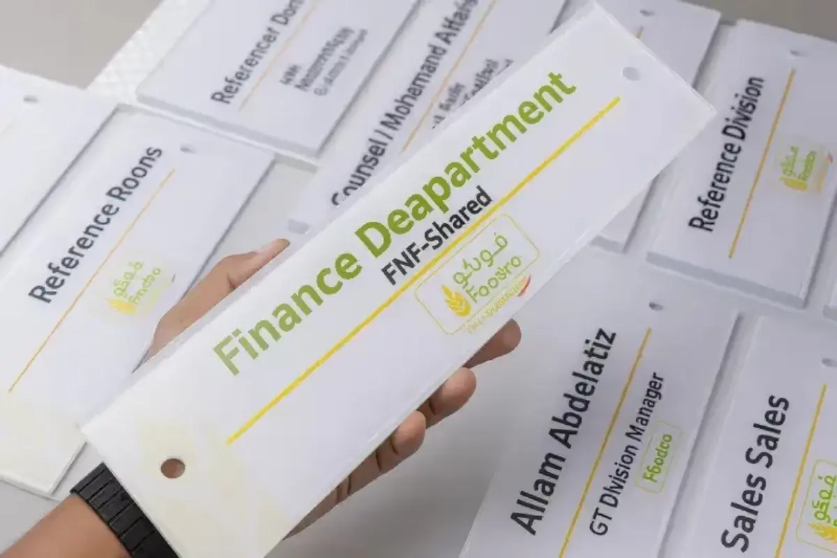 Reverse-printed acrylic door identification signs mounted with silver stainless steel mirror-finish spacers for corporate office wayfinding system in Abu Dhabi.