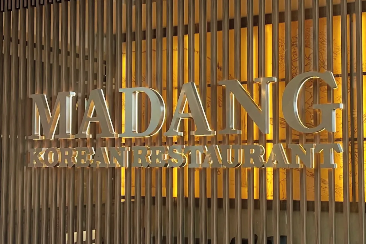 Backlit stainless steel reception signage for Korean restaurant featuring halo-effect dimensional letterforms with acrylic diffusion layer.