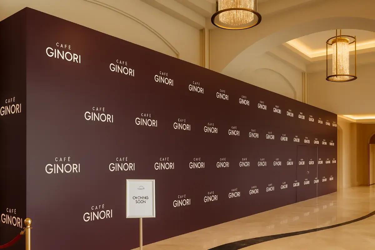 Cafe Ginori Maroon Hoarding Wall with repeated white logo pattern in Abu Dhabi, installed by Ninety Nine Advertising LLC.
