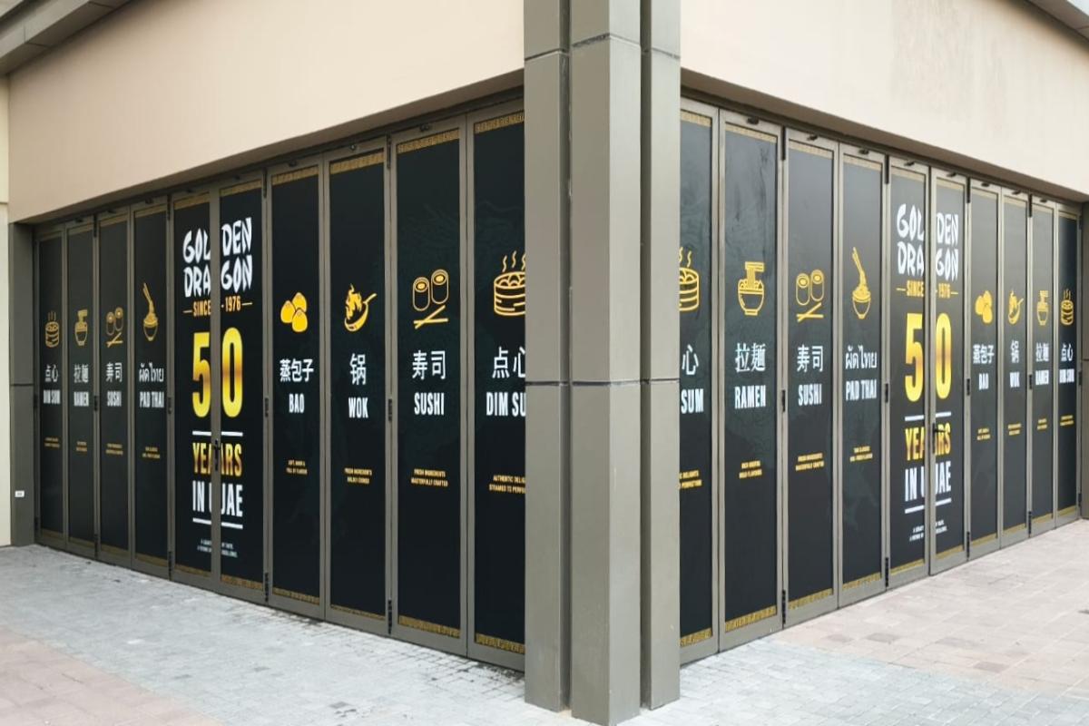 Corner view of seamlessly aligned Storefront Glass Branding on multi-panel folding doors for a restaurant in the UAE by Ninety Nine Advertising LLC