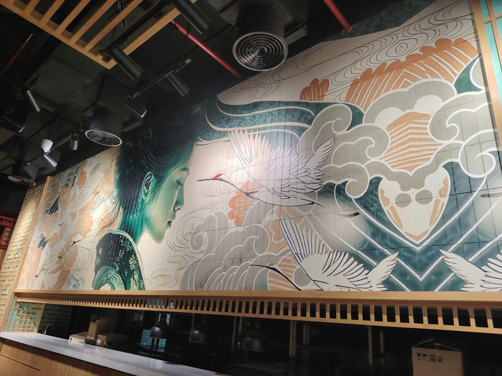 Close view of the printed portrait and crane mural across the restaurant's tiled wall
