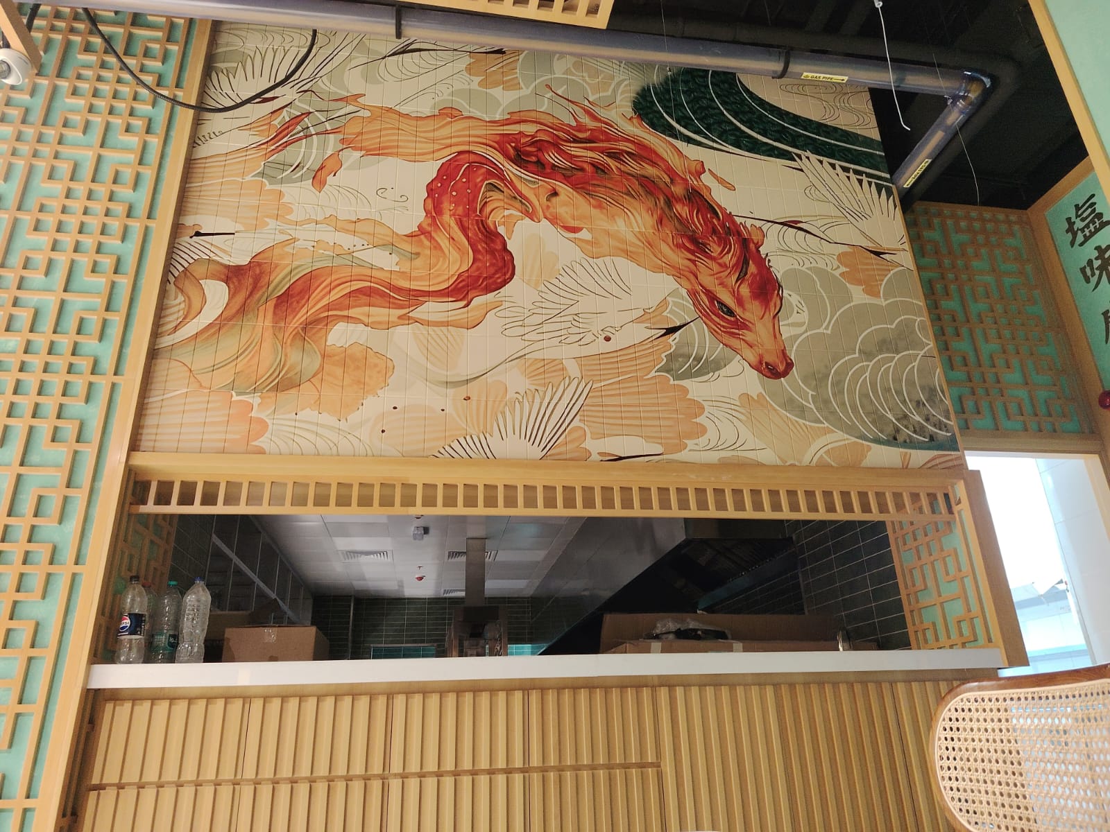 Printed dragon mural on the tiled wall above the restaurant service opening