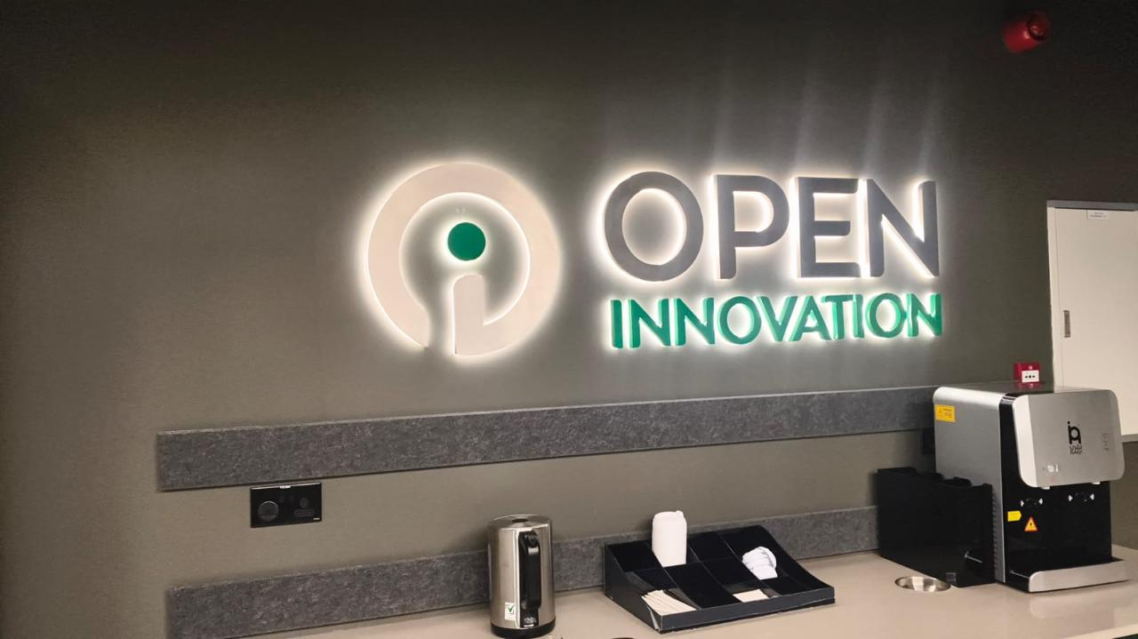Illuminated Open Innovation logo above a reception counter