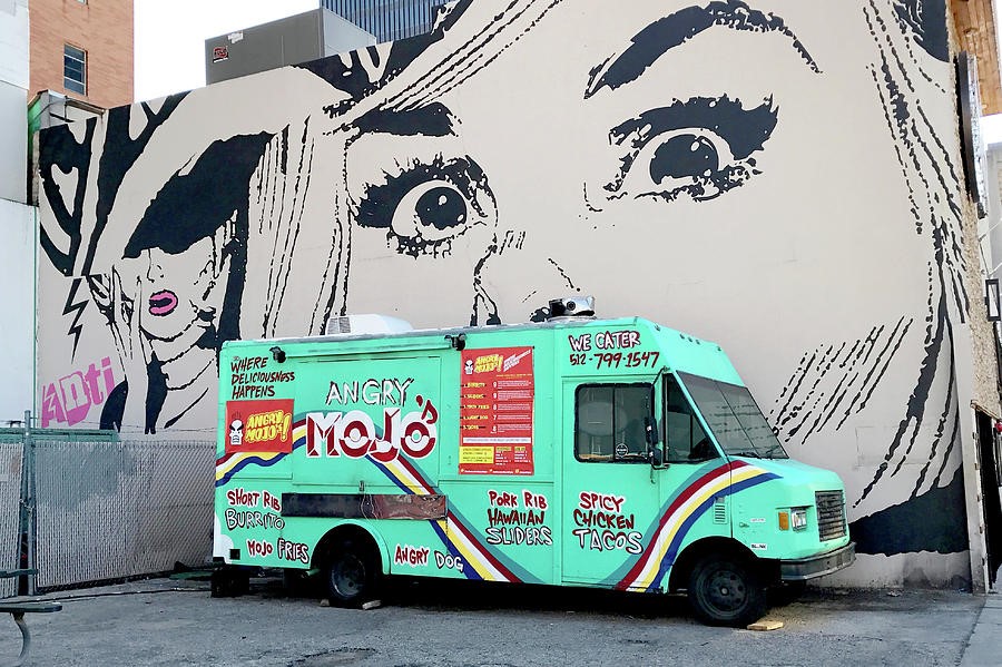 A truck parked in front of a wall with graffitiDescription automatically generated with low confidence