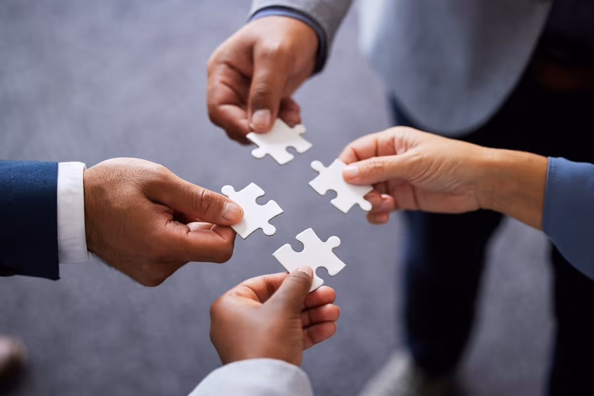Executives fitting puzzle pieces together creating synergy