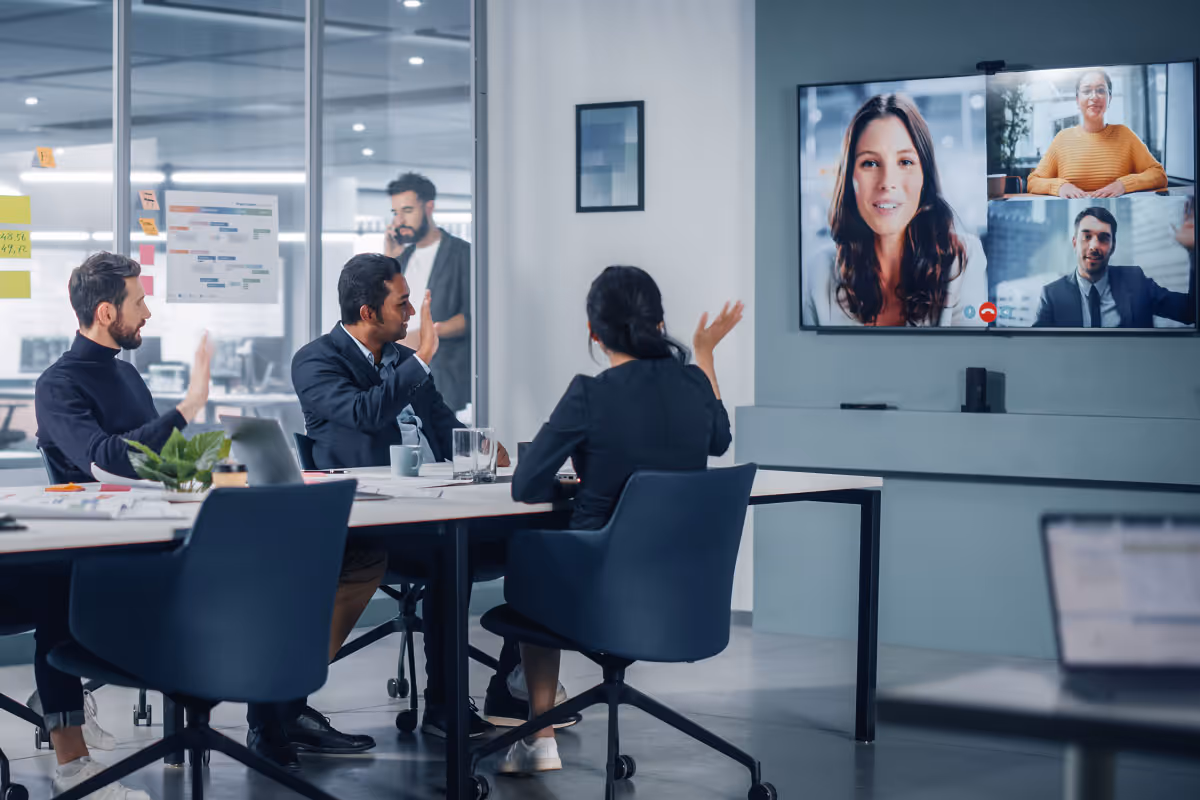 Team in a conference room on a video conference with others