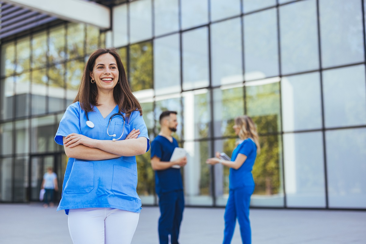Smiling medical professional outside a modern clinic, symbolizing growth and standardization across locations in a healthcare roll-up strategy