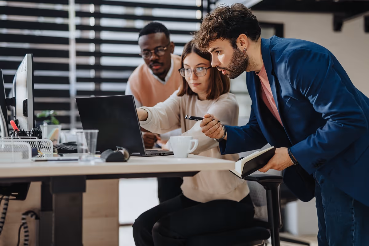Corporate development team collaborating around a laptop in a modern office setting
